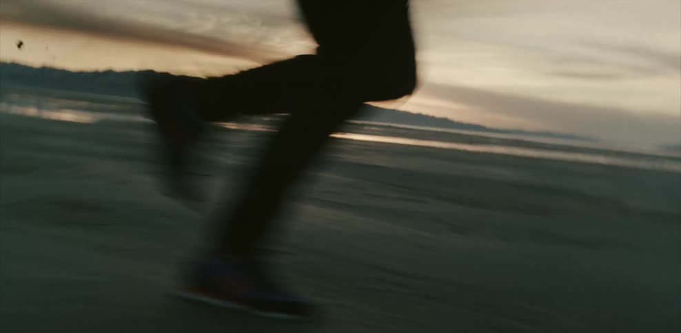 Person running quickly over marshy landscape at sunset