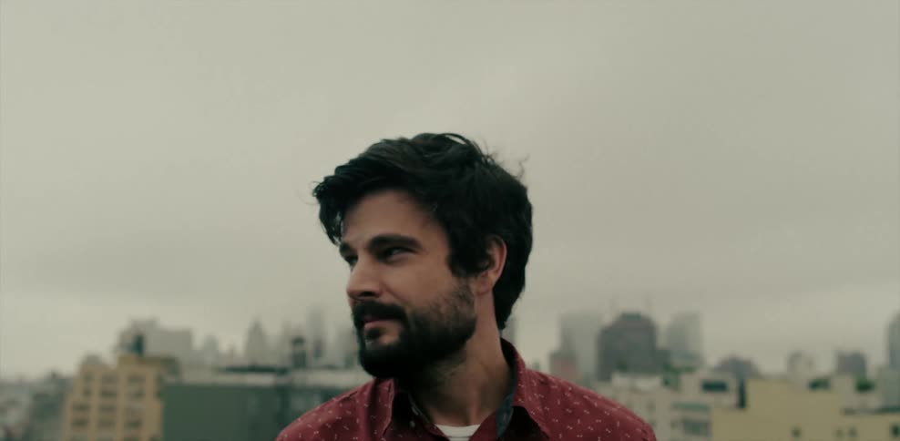 A man with dark hair looks around outside