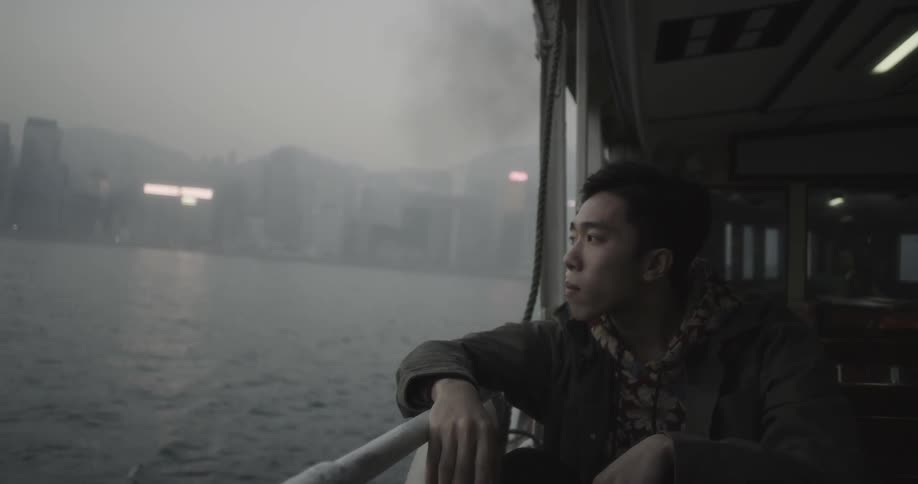 A man rides a ferry boat on an overcast day