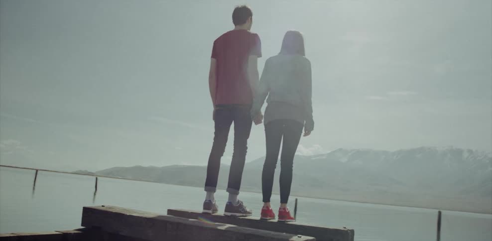 A man and woman hold hands as they stand on a pier