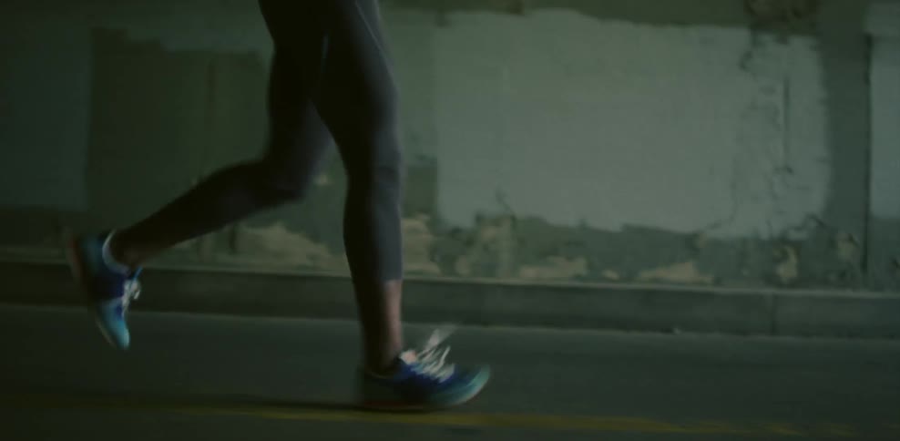A woman is jogging on the street in a tunnel during the day