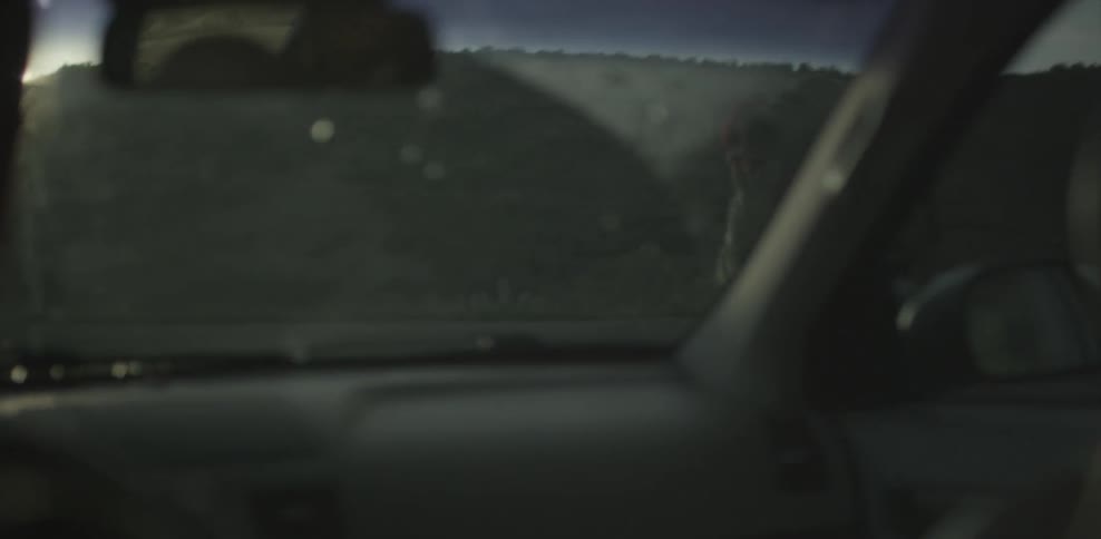 A car drives by a hitchhiker in the mountains