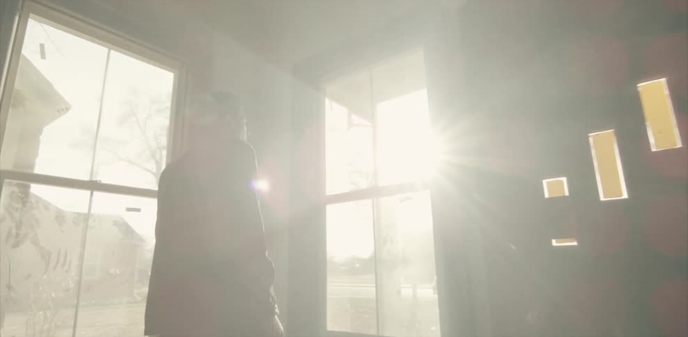 Man walking through an empty house to look out the window on a sunny day