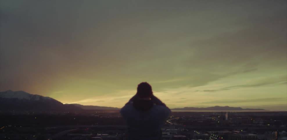 A man in a jacket rubs his head outside