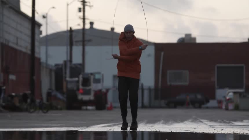 A man jumping rope outside in the road or parking lot