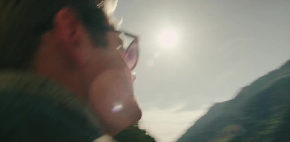 A man wearing sunglasses walks through a small rock tunnel