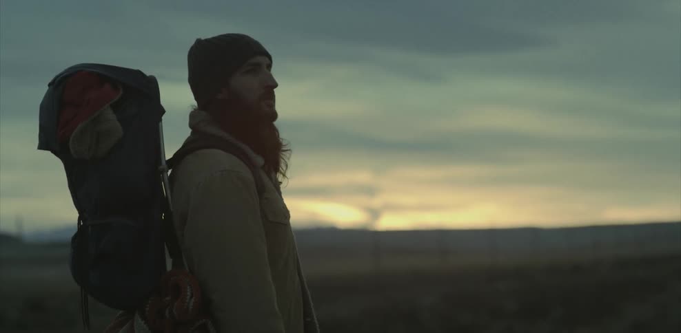 Man wearing a backpack looking out at flat land