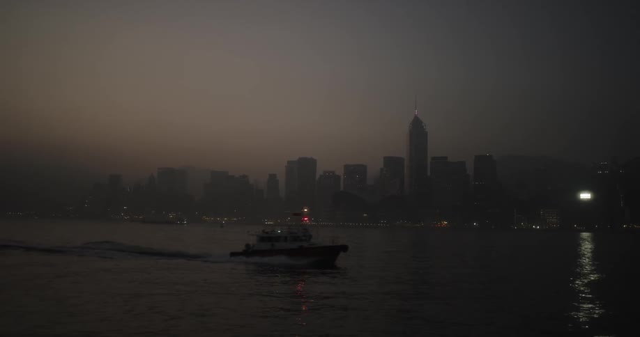 A person sails a boat past the foggy city