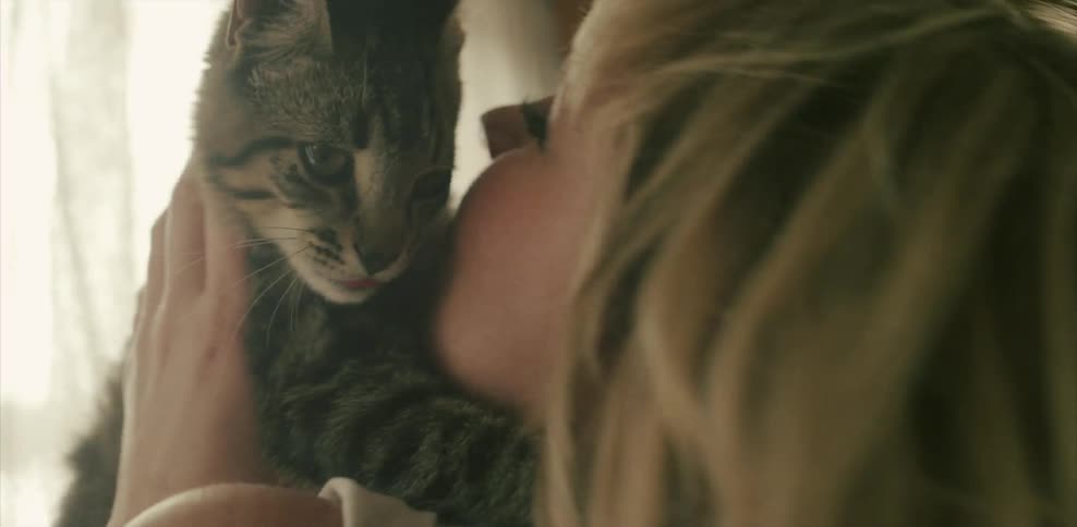 A blond woman kisses and pets her cat