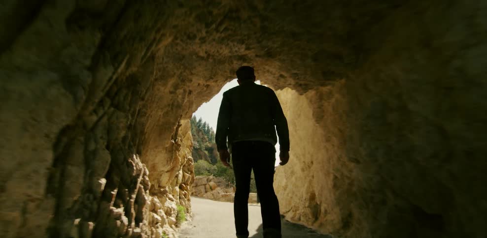 Man walks through a tunnel out into the sunlight