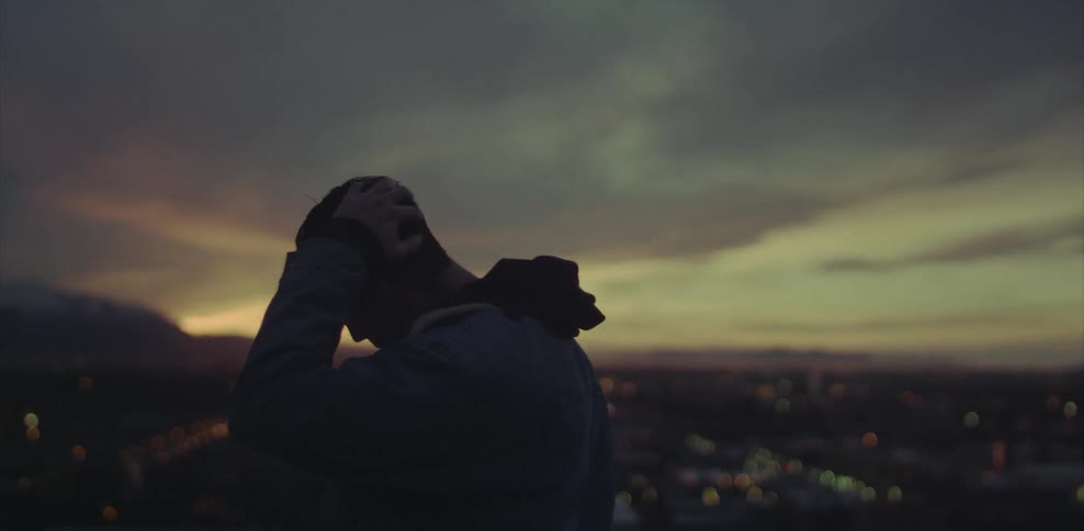 Man brushing head with hands overlooking at city