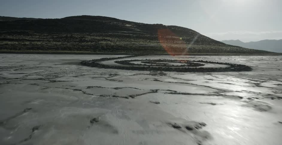 A stone spiral stretches out from a hill onto a salt flat