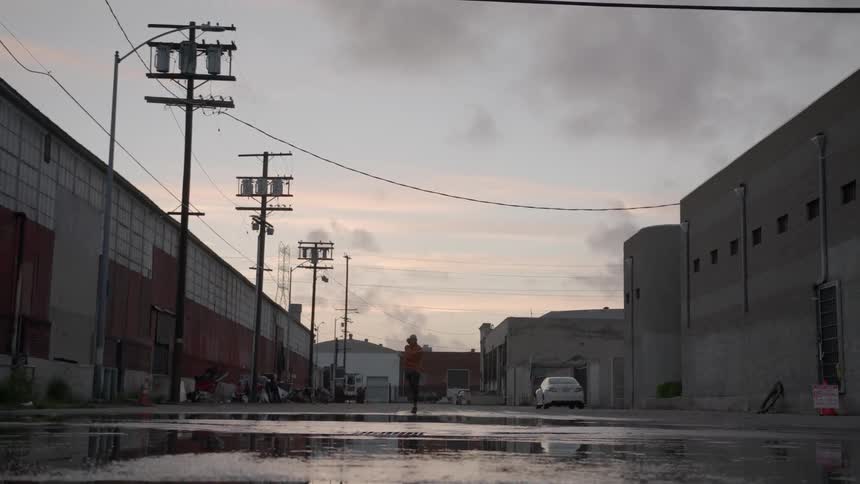 A man uses a jump rope near puddles in a city setting