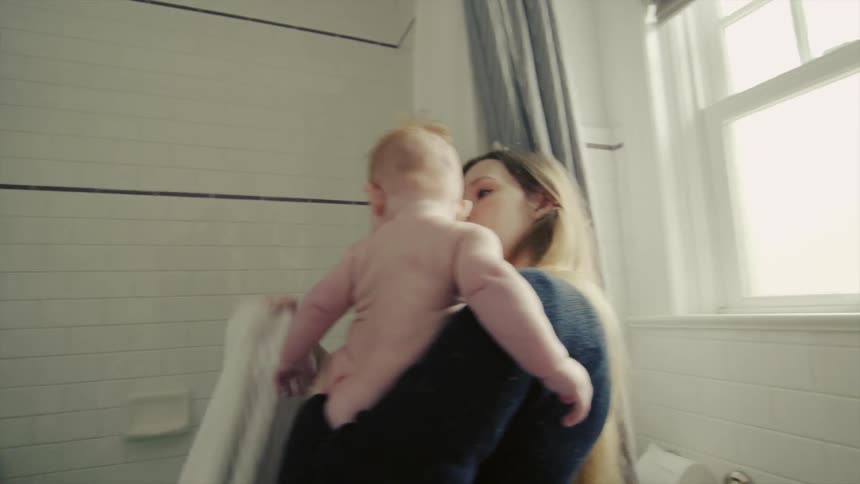 A woman lifts a baby out of a bathtub and covers it with a towel