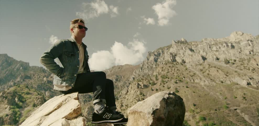 Man sitting on a rock overlooking mountainous landscape