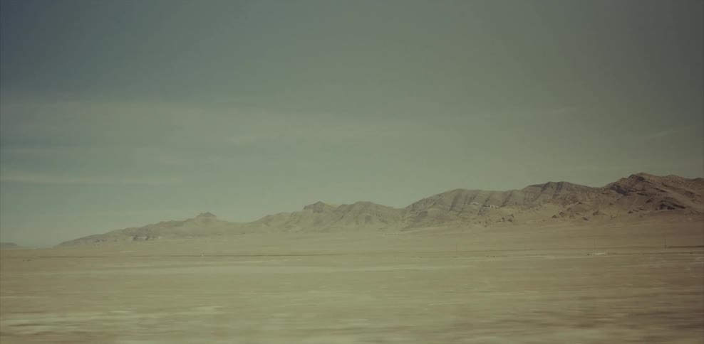 Moving fast past a desert with a mountain in the distance