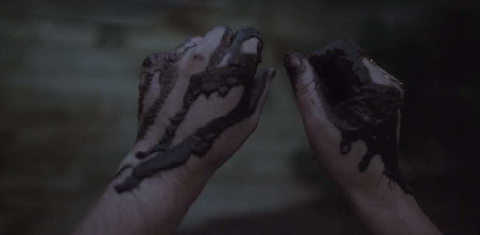 Hands turning over covered in mud