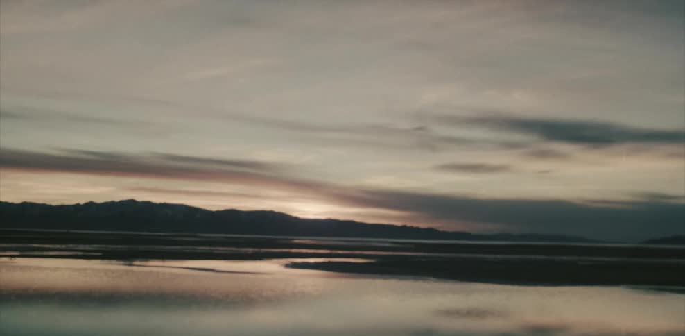 A view of a mountain with a lake at sunset