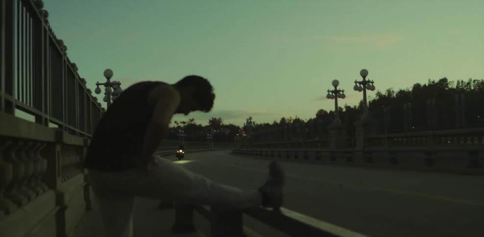 Man stretching his leg on a barrier as a bus drives past