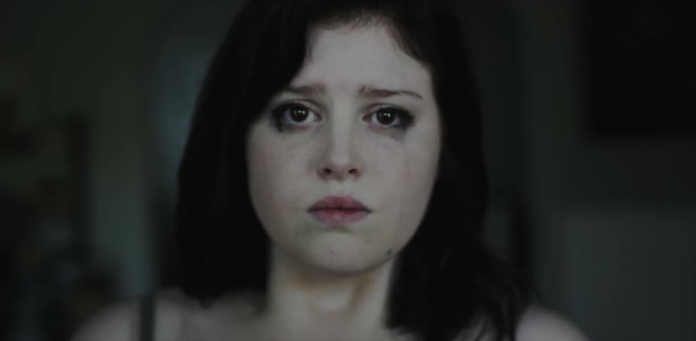 A tear runs down a woman's face as she draws in a breath