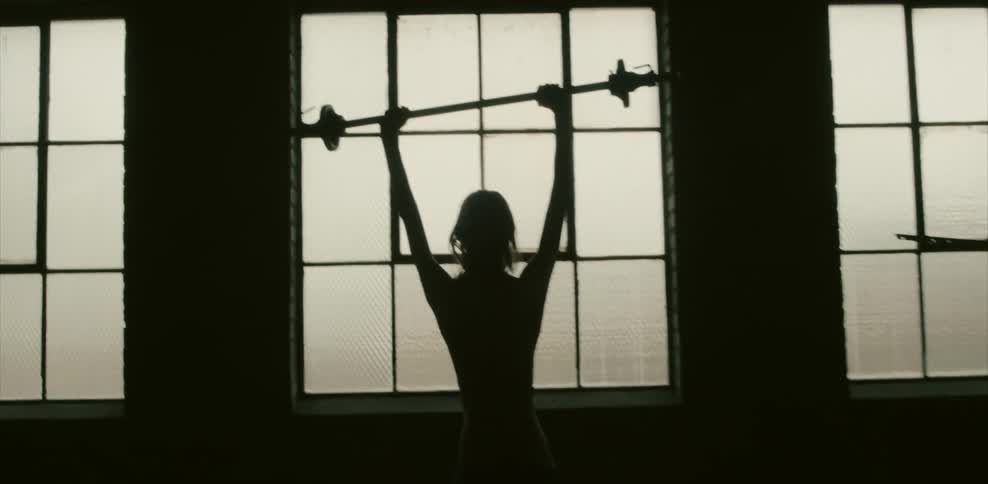 A person is holding a barbell in a dark gym