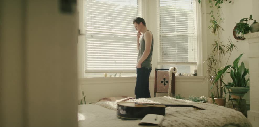 Man stands next to a window in a bedroom