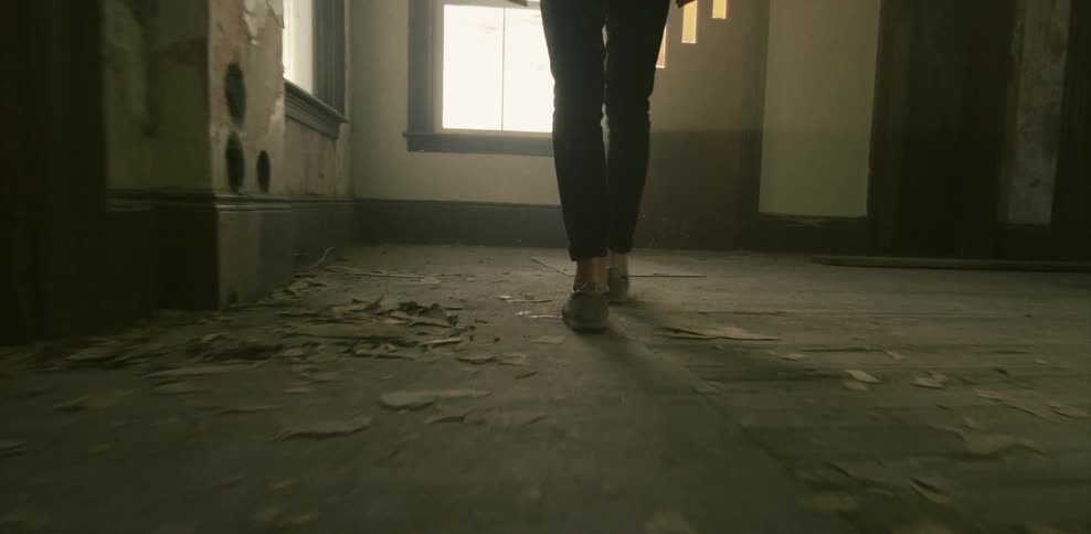 Person walking through an empty room to look out a window
