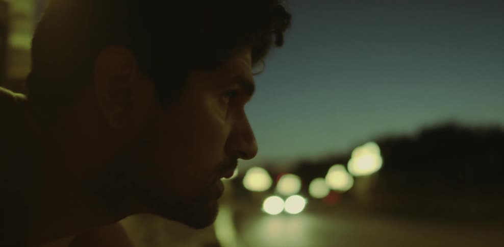 Man leans on a guardrail watching cars pass by