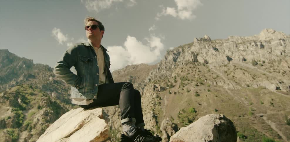 Man sitting on a rock overlooking mountainous landscape