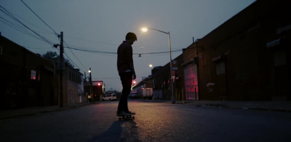 A man skateboards in an alley during the evening
