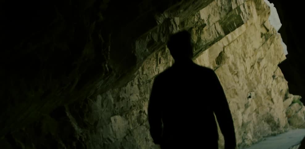 Man walks out of a cave on a sunny day