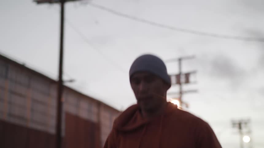 A man is skipping rope outside at dusk