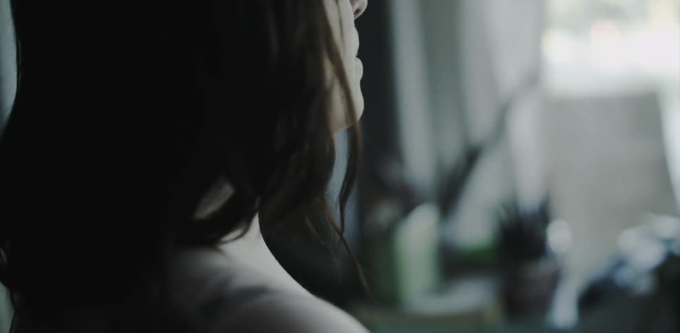 Sad looking woman in a living room stares downwards