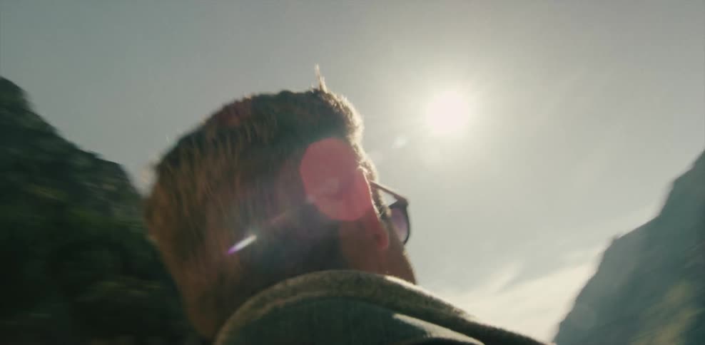 A man in sunglasses walks through a rock tunnel