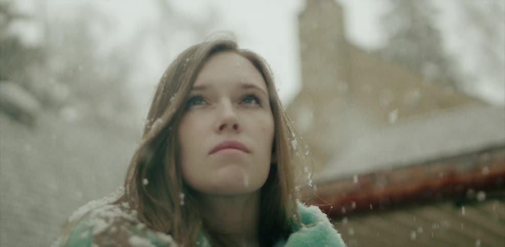A woman looks up at the falling snow
