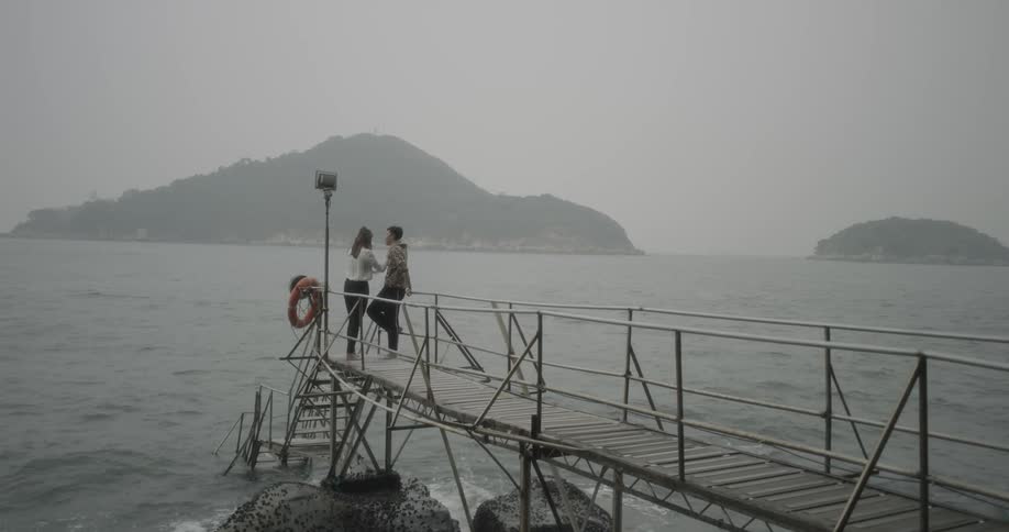 Man and woman standing at the edge of a dock by a lake