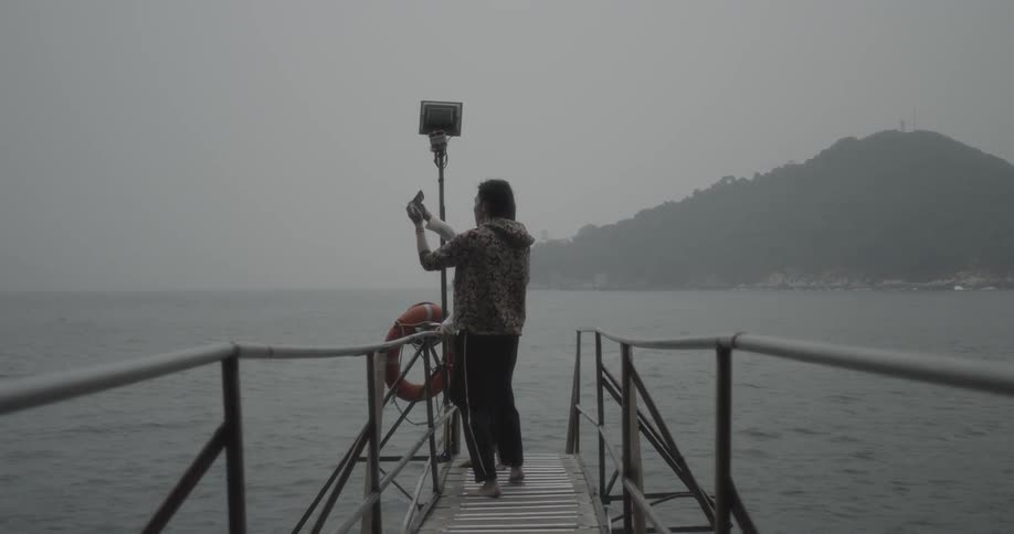 Man and woman stand on a dock taking pictures of the lake