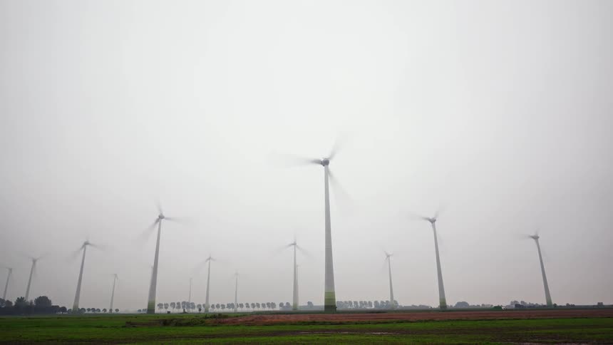 Many wind turbines spin on a cloudy day