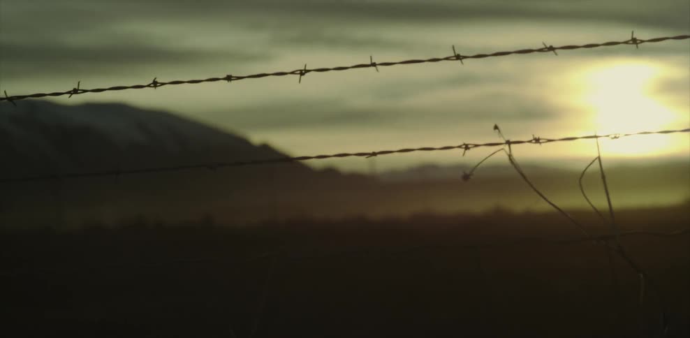 A view of the sun setting over a field and mountain