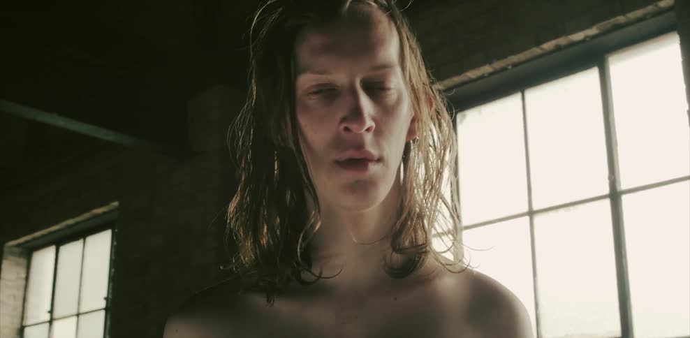 A man stands in front of a window blinking his eyes