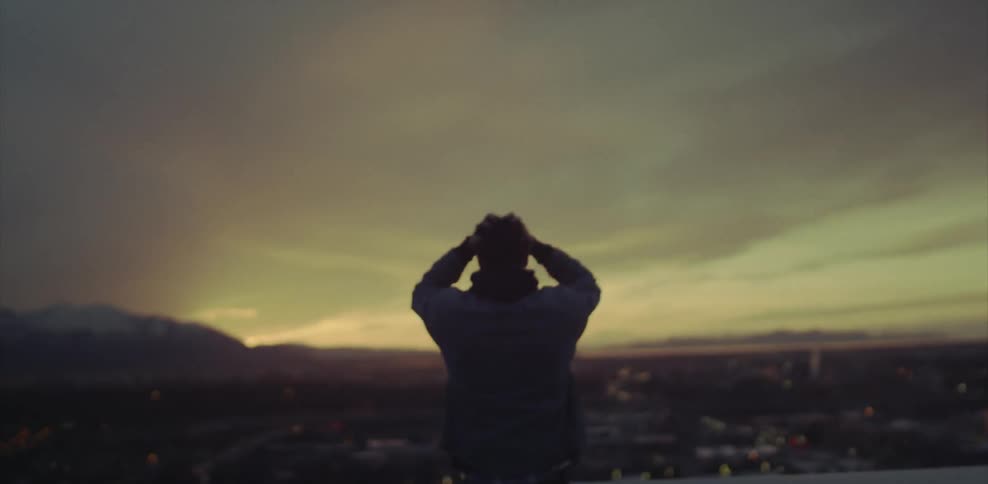 Man looking out at mountains raising arms over head