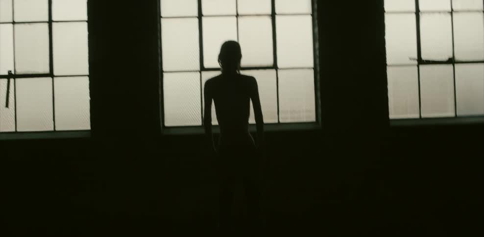 A person is standing by a large window in a warehouse