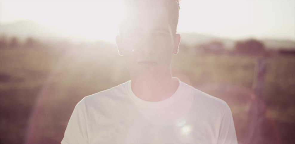 A man is standing on a field at sunrise