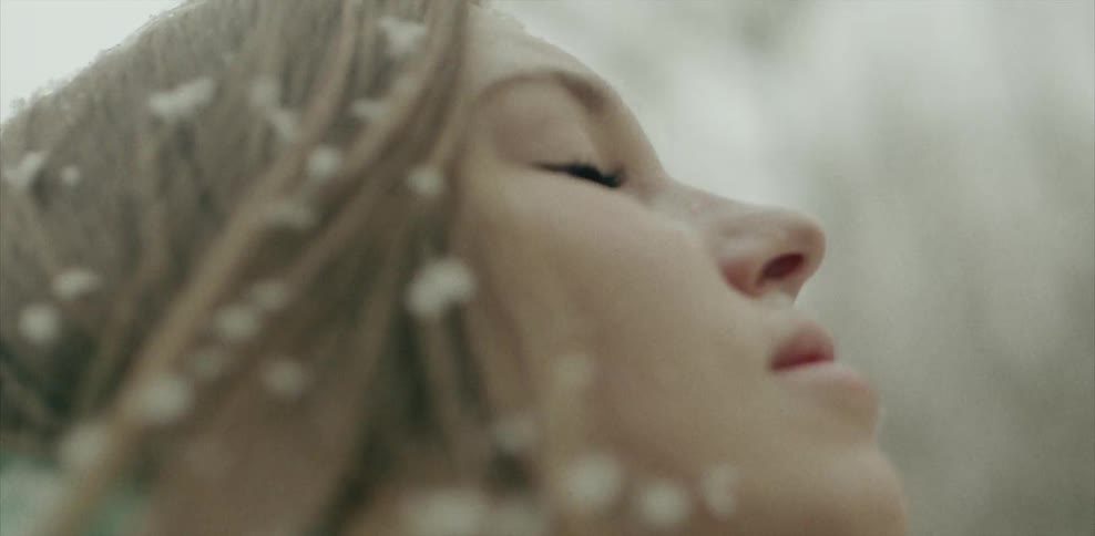 A woman looks up as the snow falls on her face
