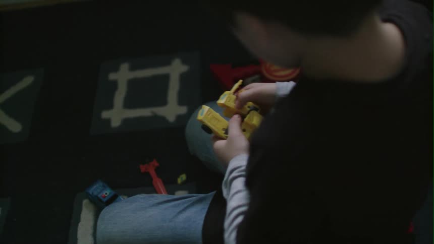 A boy plays with toys while sitting on the floor