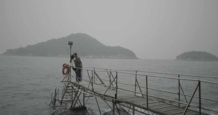A man and women kiss on the pier