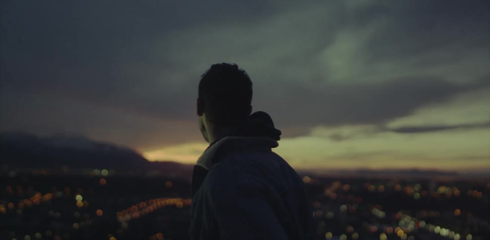 Man running fingers through his hair while looking down at a city