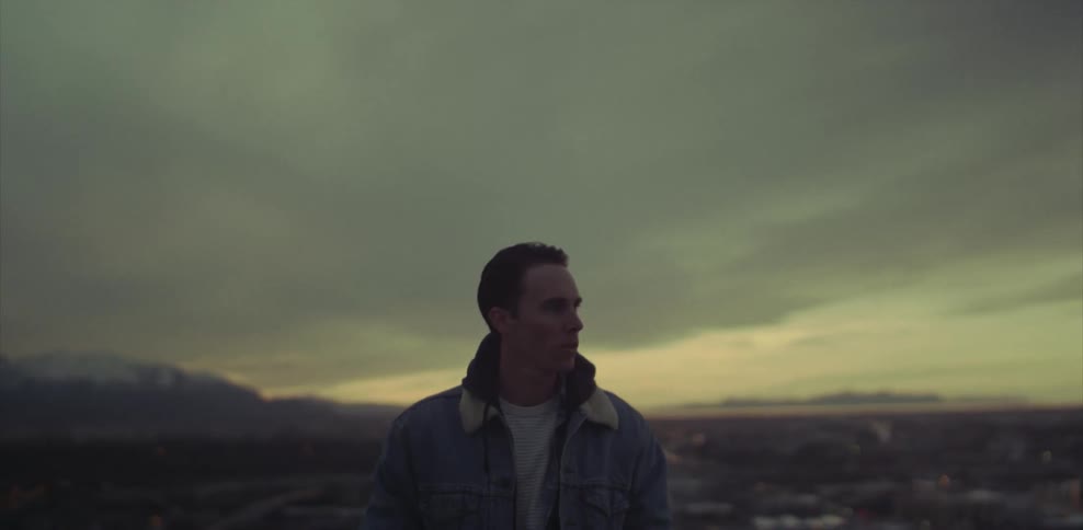 A man in a denim jacket standing outside