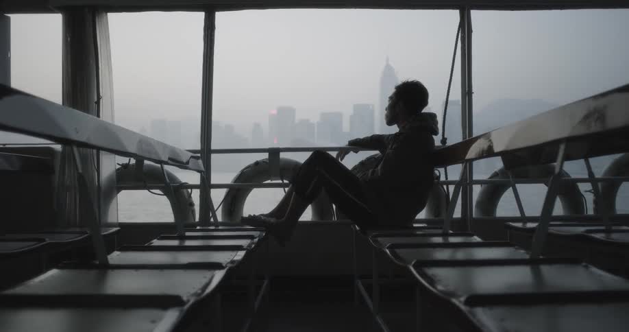 A man rides a ferry boat on an overcast day