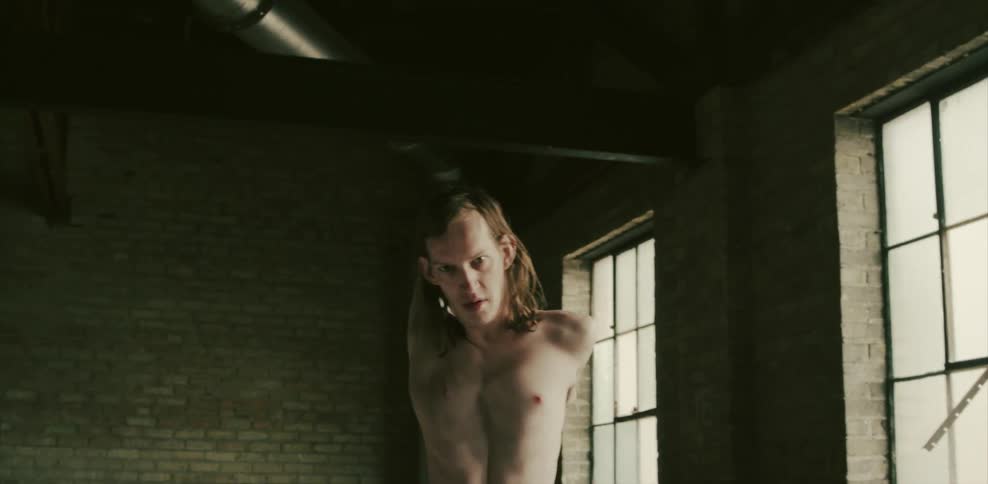 A thin man stretches his arms behind his back